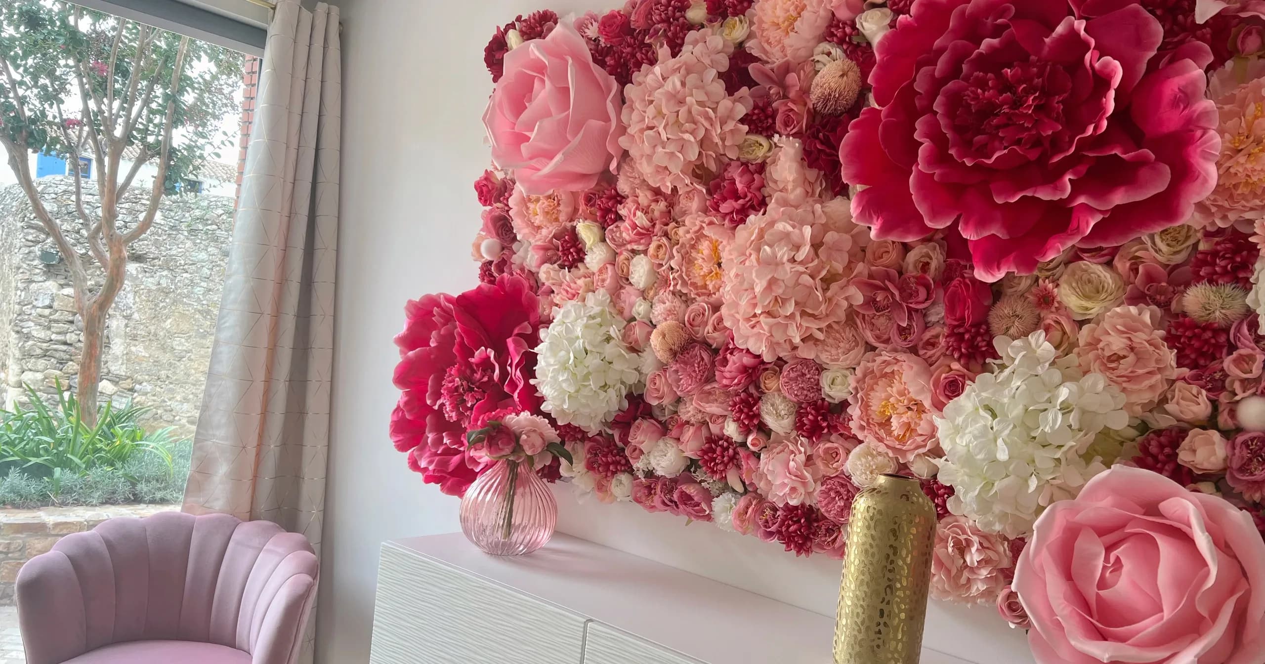 Mur floral rose de l’institut Mademoiselle M, près de la fenêtre et du fauteuil d’accueil